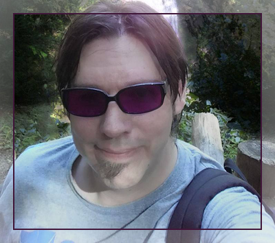 Older selfie in sunglasses, outdoors among trees.